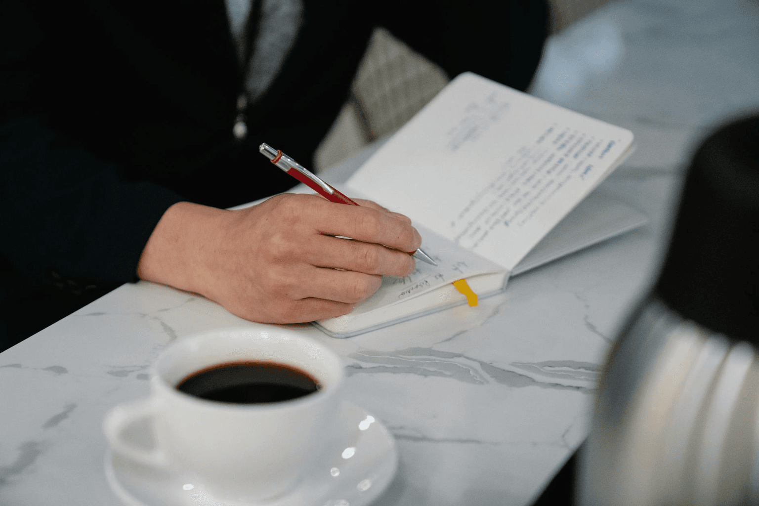 Open journal with neat repetitive handwriting beside morning coffee in warm golden light