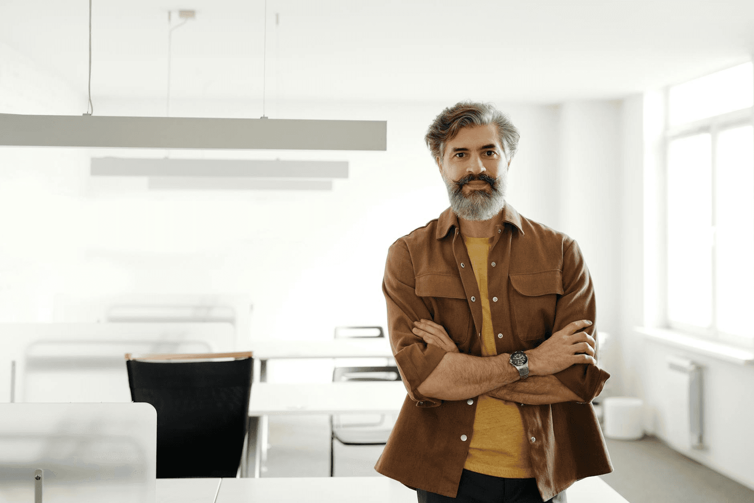 Confident entrepreneur standing with arms open in a bright modern space, representing success mindset