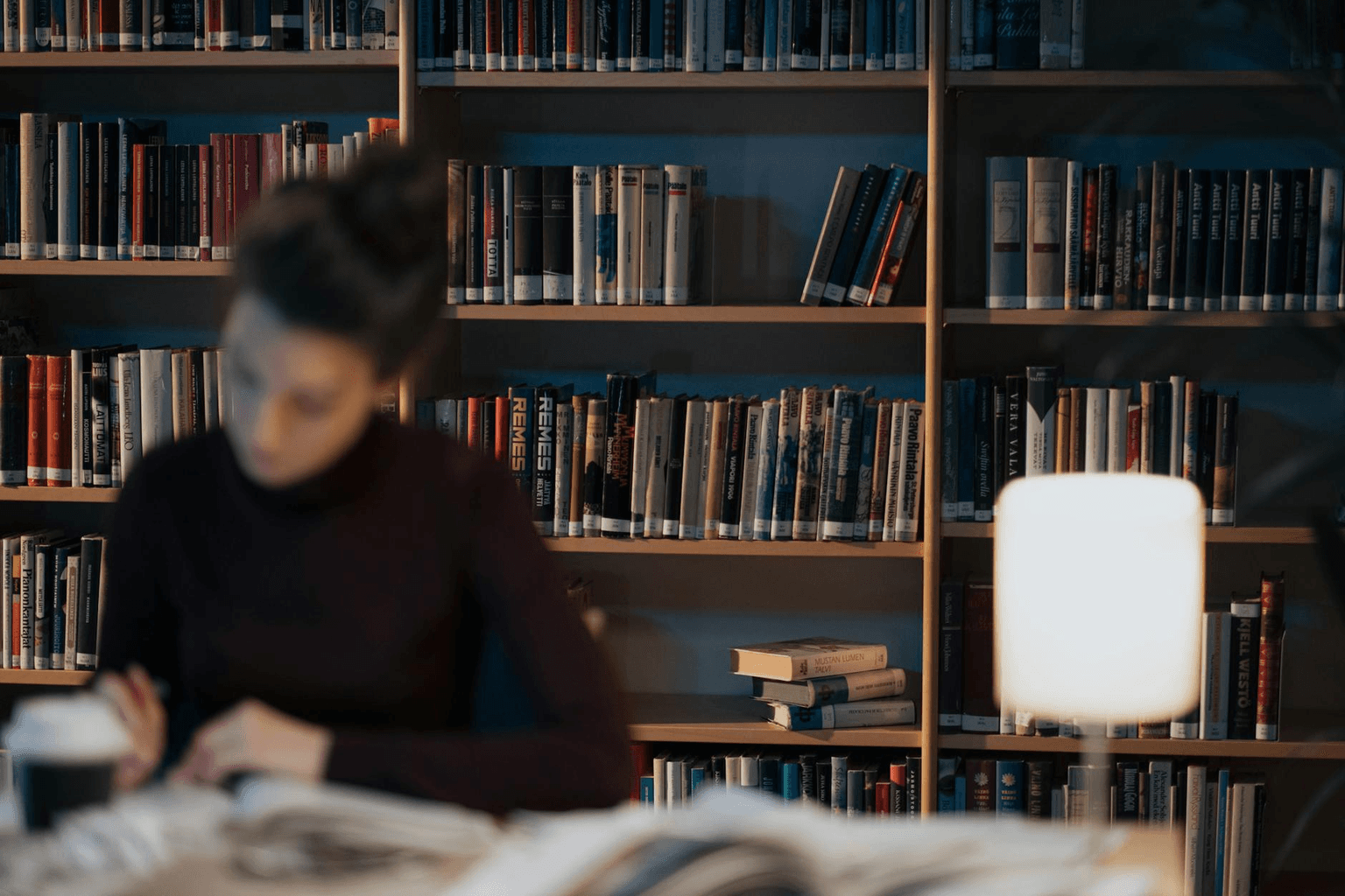 Student studying at a desk with books and warm lamp light, focused and calm