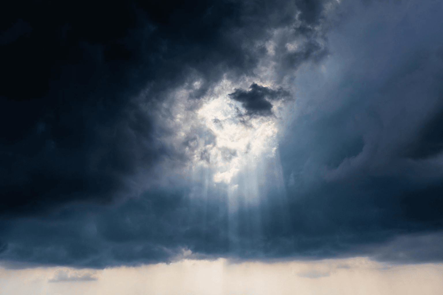Dark storm clouds parting to reveal golden sunlight representing the shift from negative to positive thinking