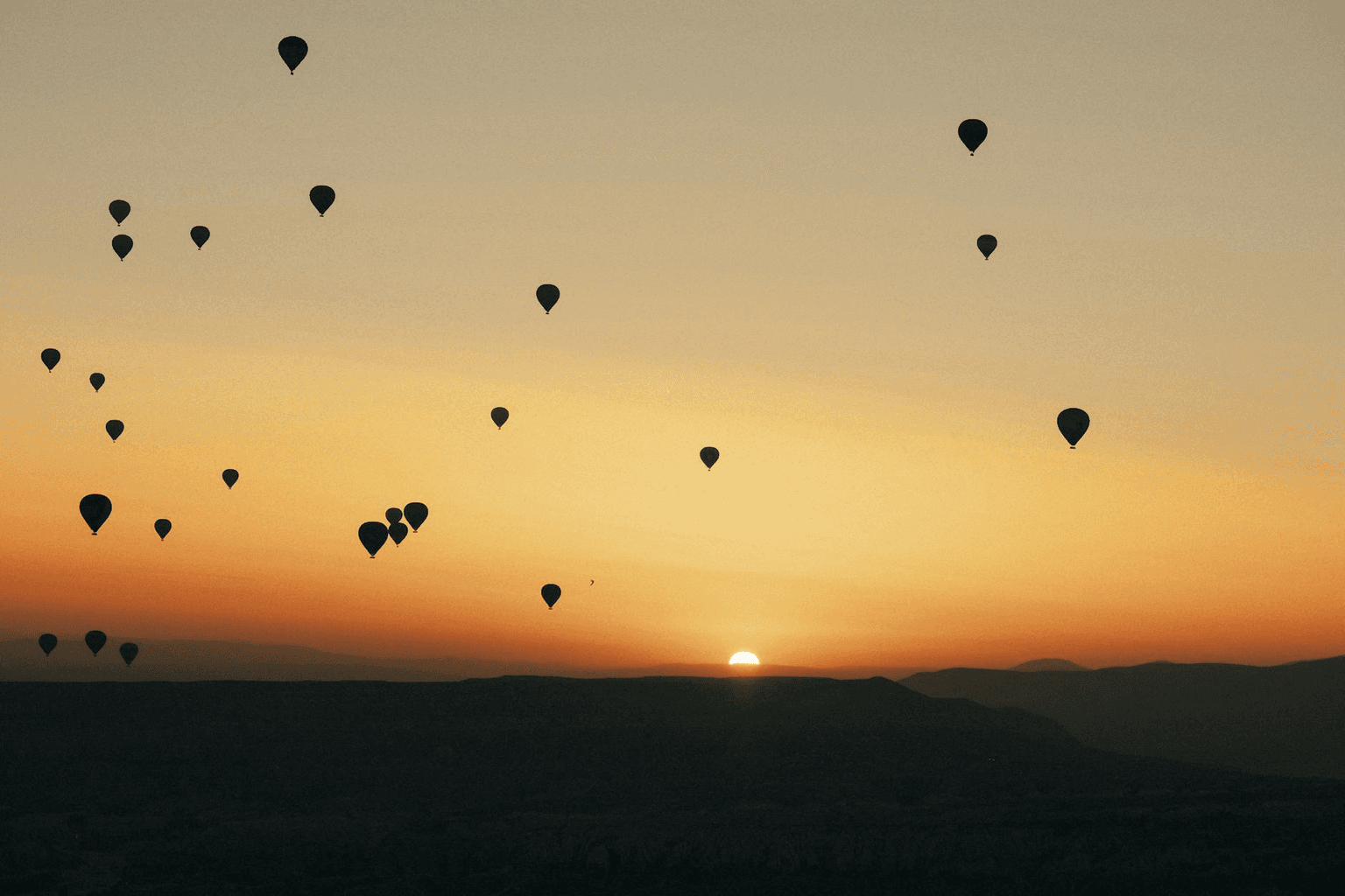 Person releasing a glowing balloon into a vast open sky at golden hour representing surrender and release