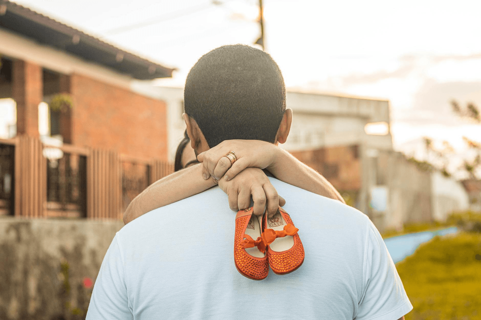 Warm golden light on baby shoes and a small pair of hands representing hope, fertility, and new life