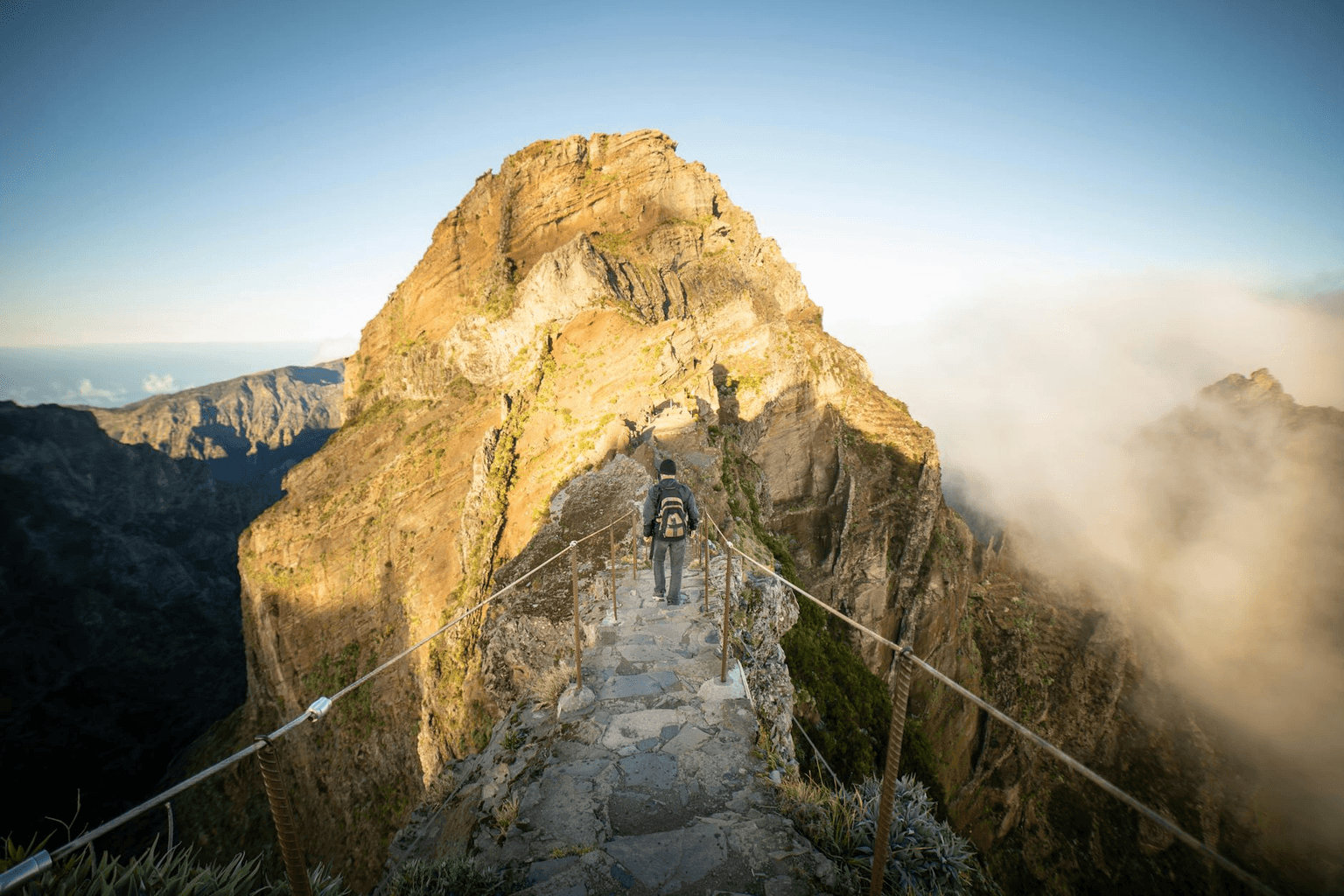 Mist clearing over a mountain path to reveal a clear sky and open road ahead