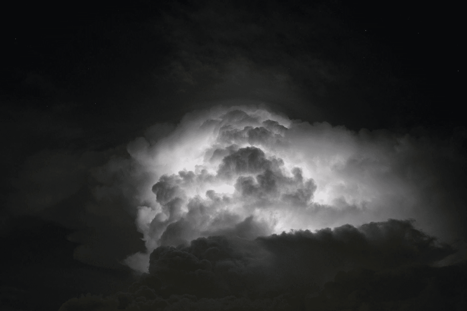 Person standing in rain with a beam of golden light breaking through storm clouds above them
