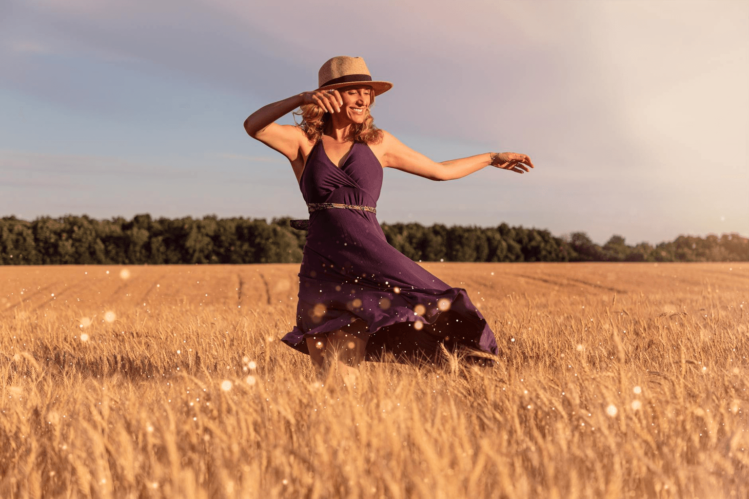 Person laughing freely in warm golden sunlight in an open field