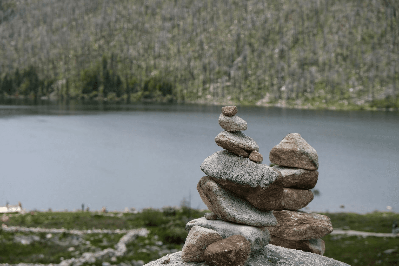 Person sitting in peaceful meditation by a still mountain lake at dawn