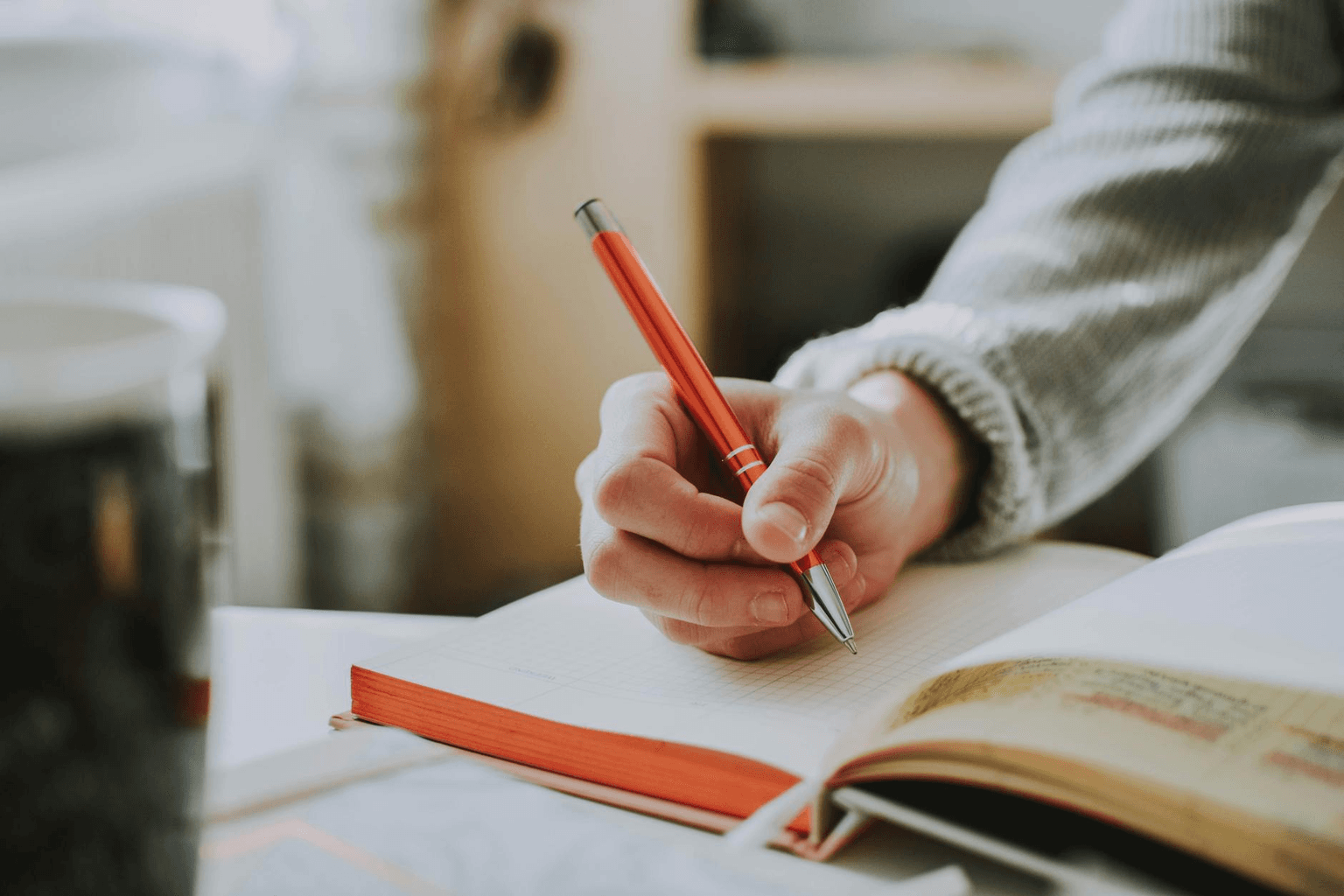 Hand writing in a journal with a pen in warm golden morning light