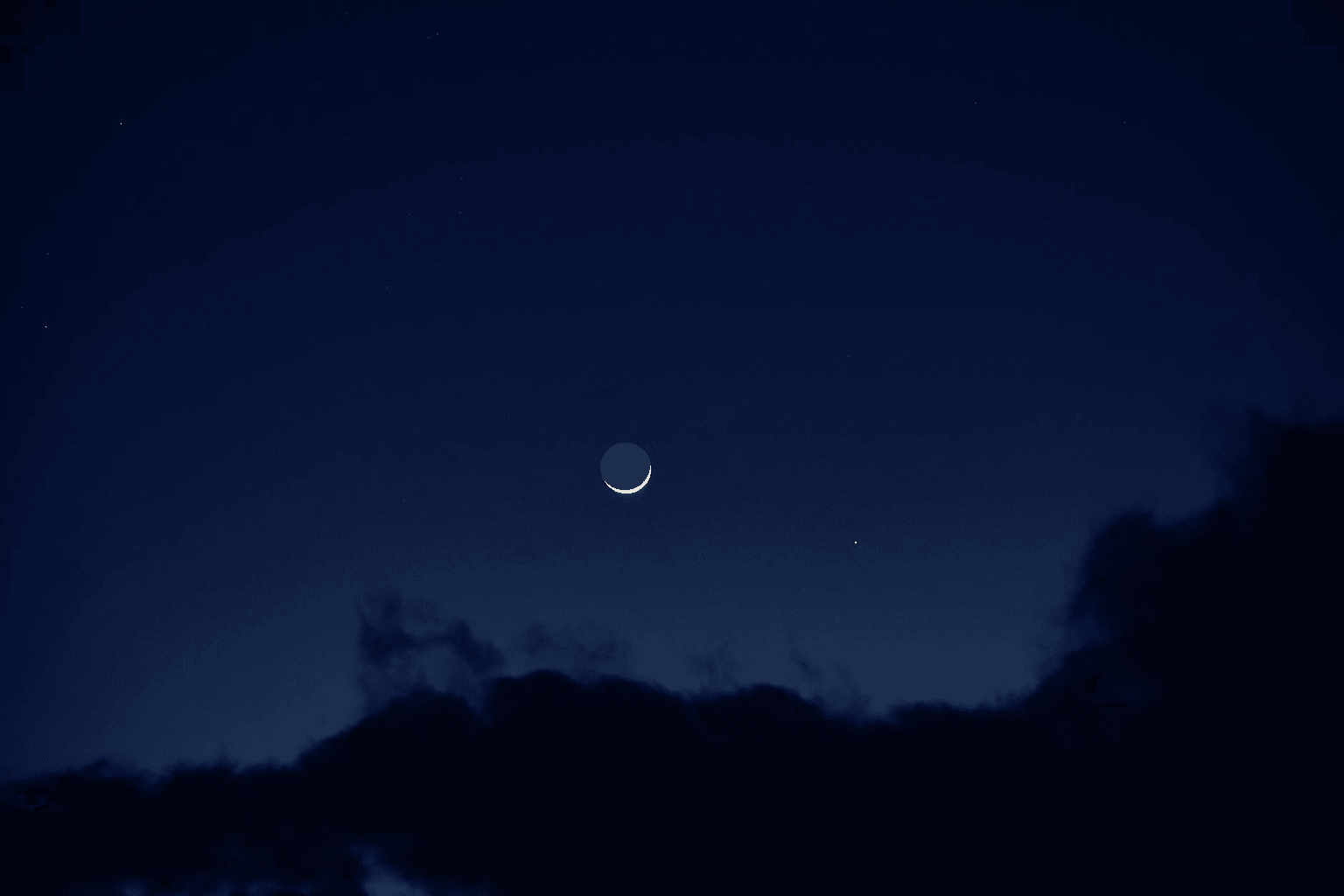 Dark night sky with a sliver of new moon and scattered stars representing new beginnings and intention setting