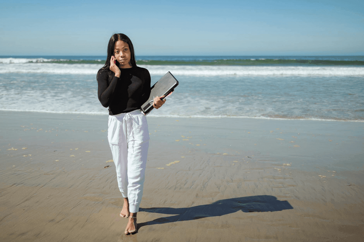 Person working on laptop at a beautiful outdoor location overlooking the ocean representing financial freedom and location independence