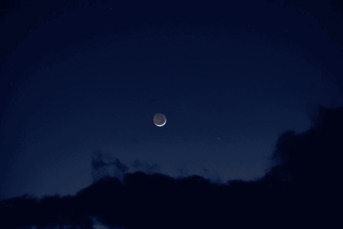 Dark night sky with a sliver of new moon and scattered stars representing new beginnings and intention setting